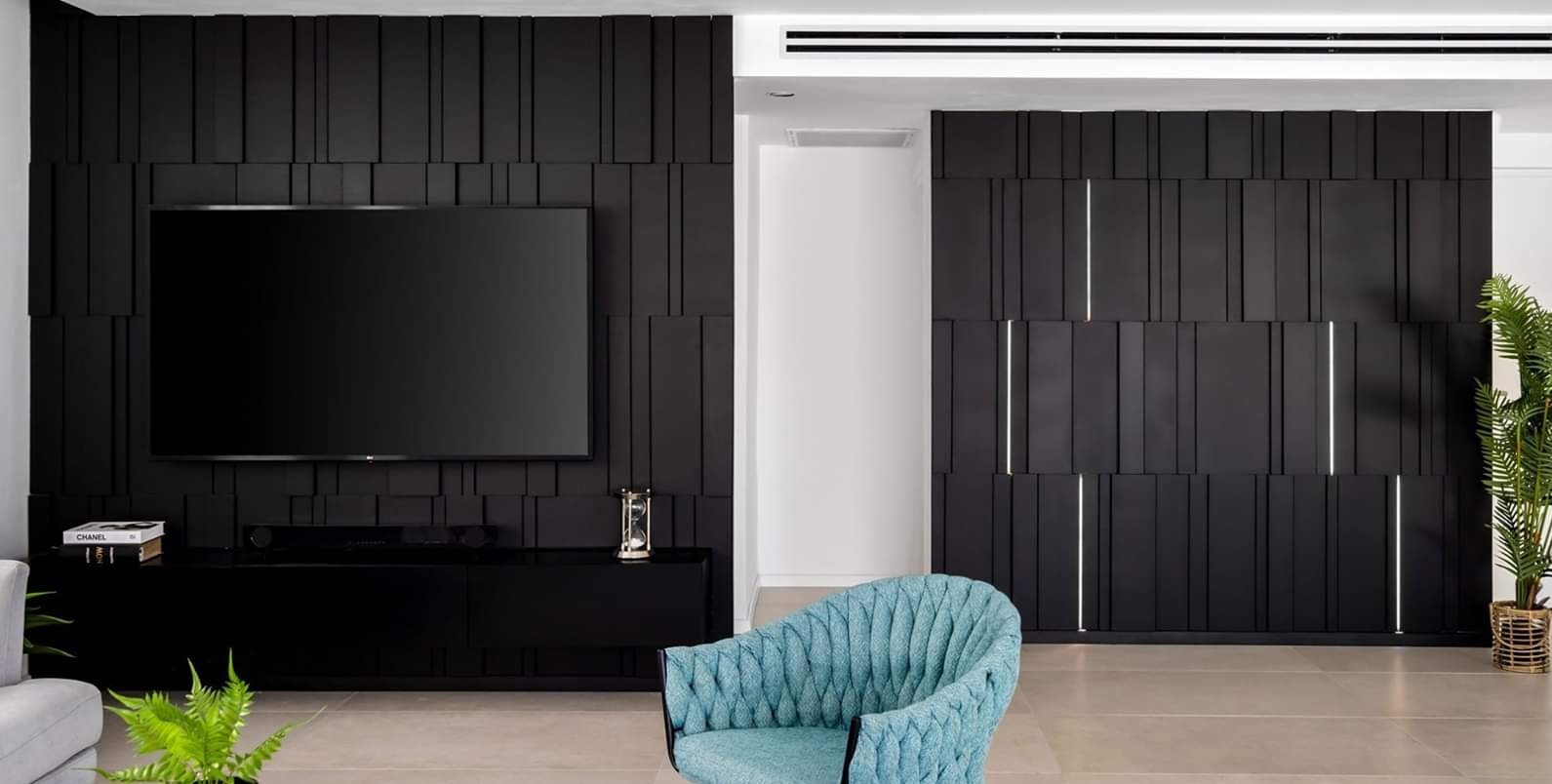 Fluted dark wall with concealed door leaves — custom media wall by iKitchen Cabinetry